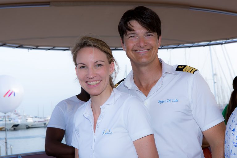 Captain and hostess in white uniforms on the flybridge of a charter yacht