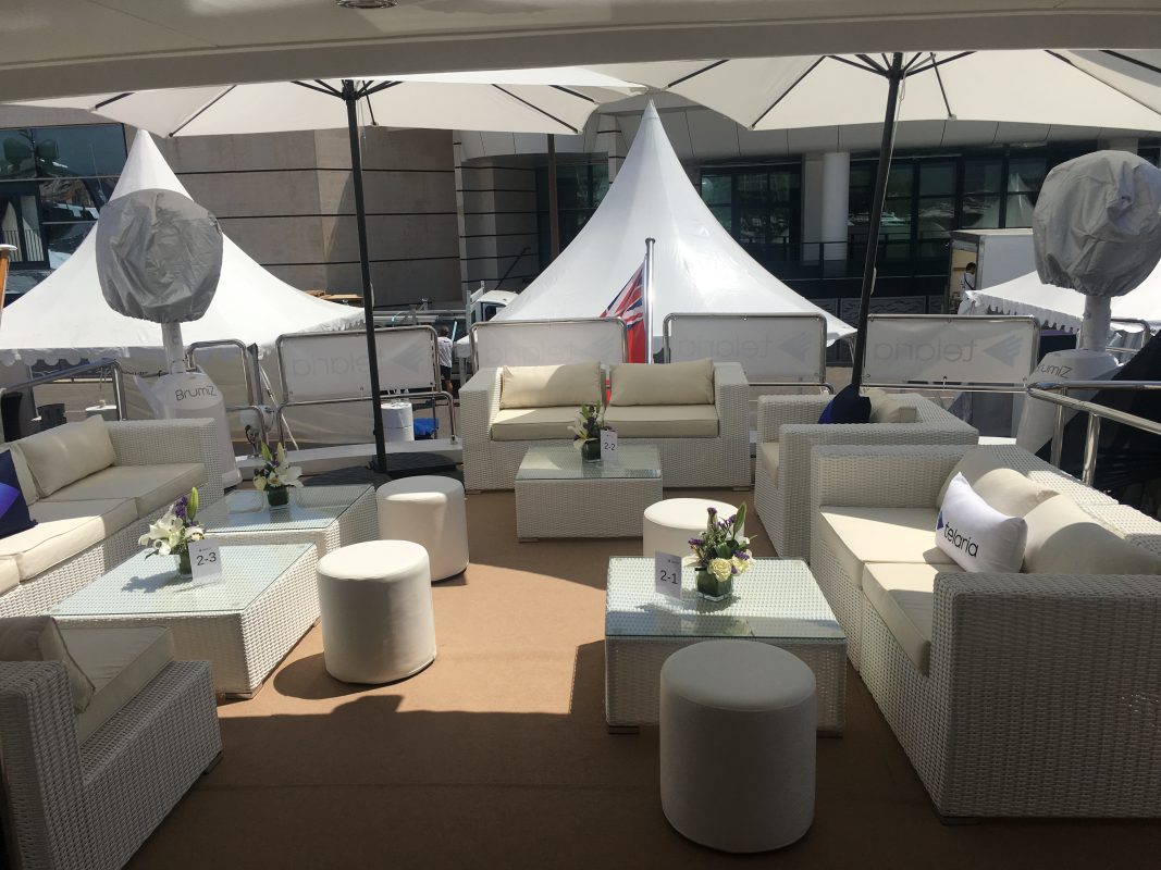 White dock tents with a lounge area on the quay beside a yacht in Cannes