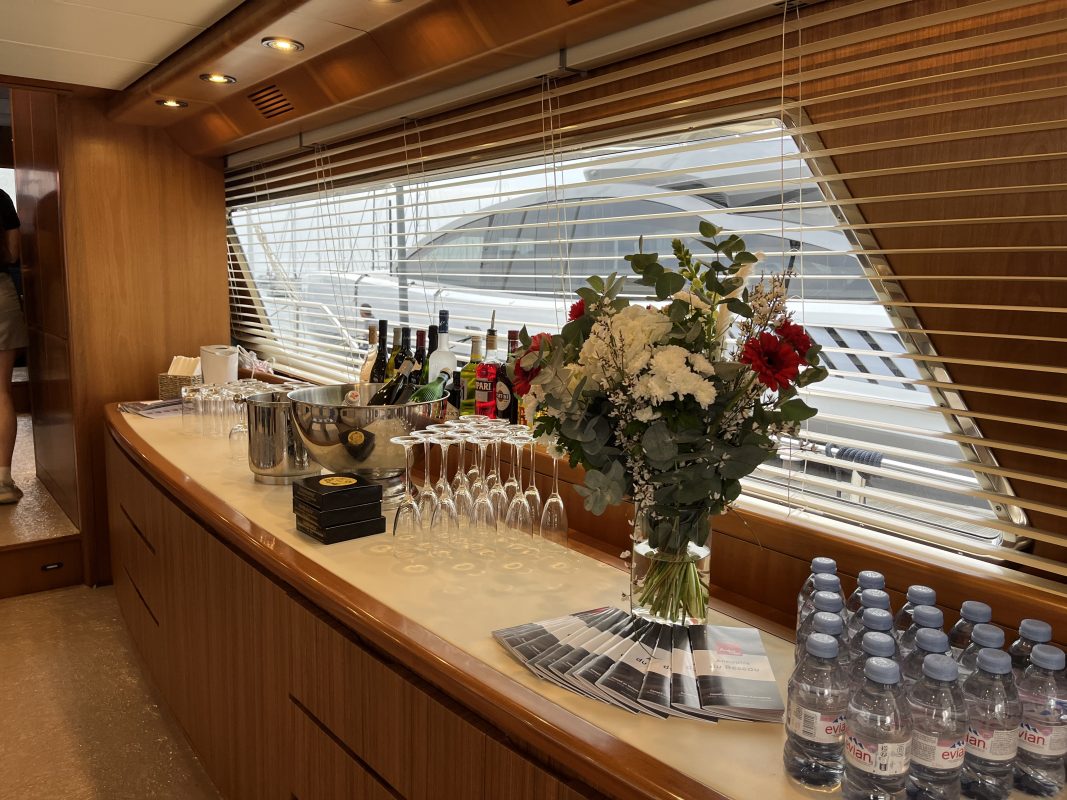 Wooden bar with fresh flowers and water bottles inside a yacht