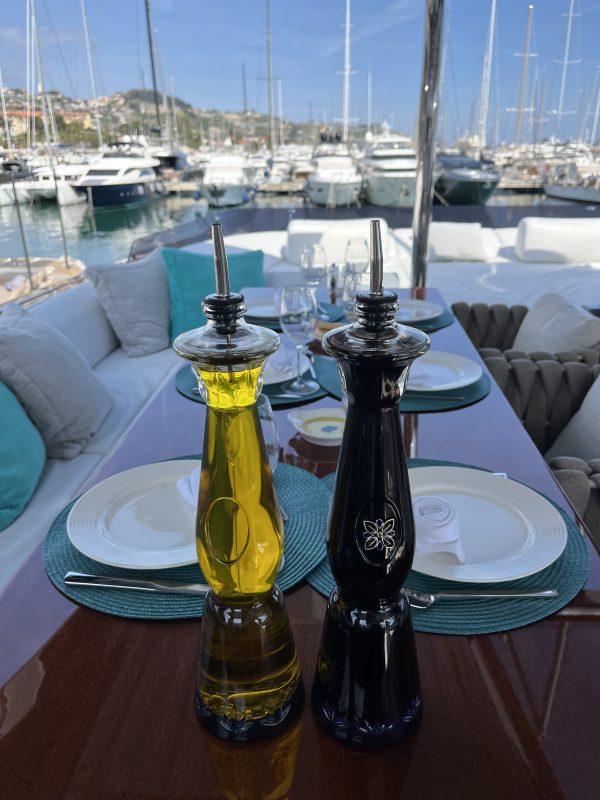 Table set with plates and olive oil on a yacht deck in Cannes