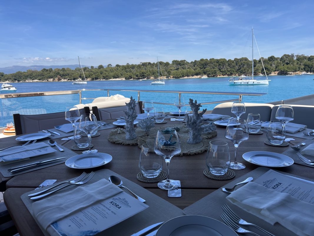 Table set for lunch on a yacht deck with a view of the bay of Cannes