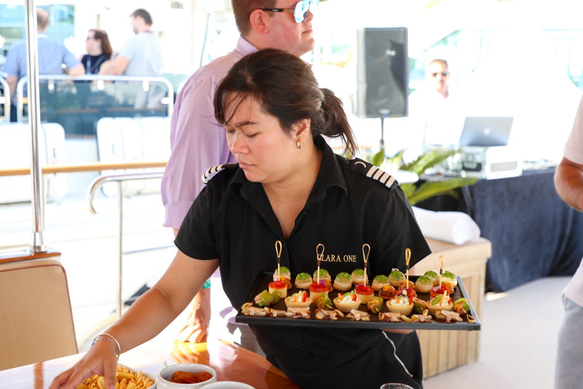 Yacht hostess serving canapés on a tray during a corporate reception on board