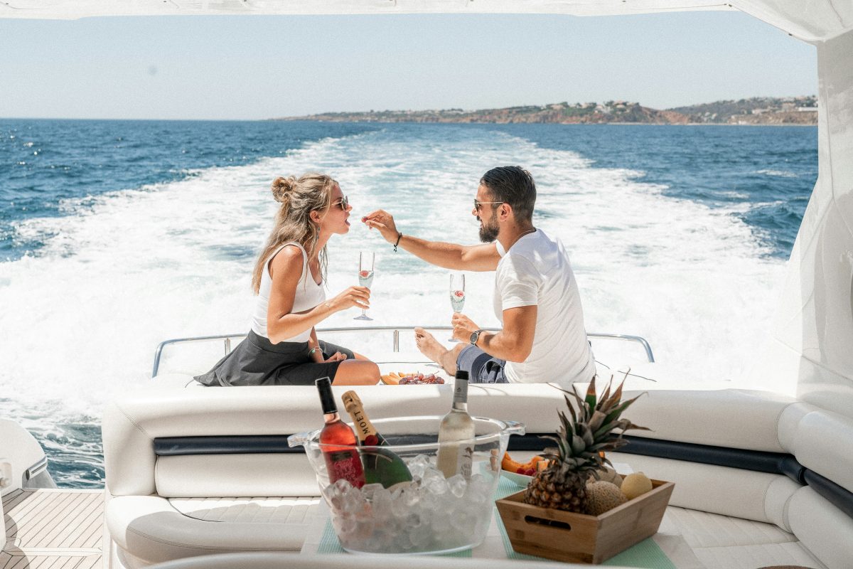Two guests toasting with champagne on the aft deck of a motor yacht with the wake behind