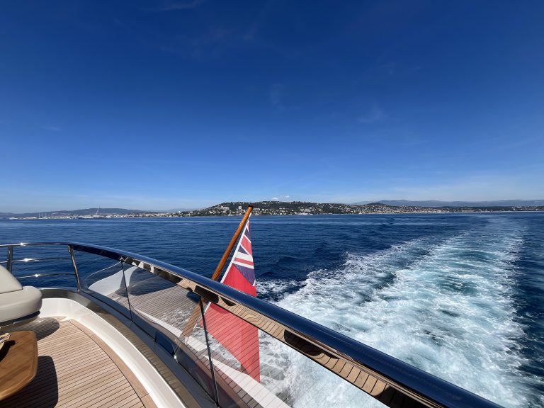 View from the stern of a motor yacht leaving Cannes, with the wake and the coastline behind