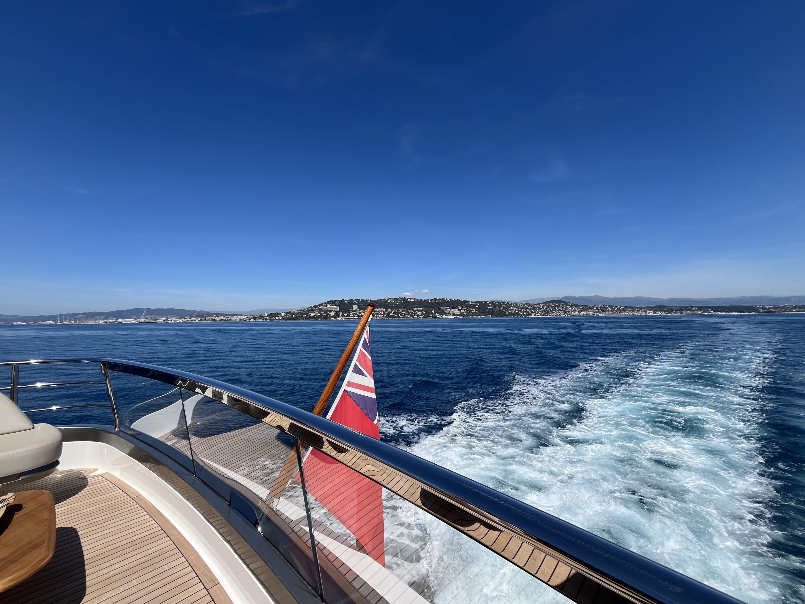 View from the stern of a motor yacht leaving Cannes, with the wake and the coastline behind