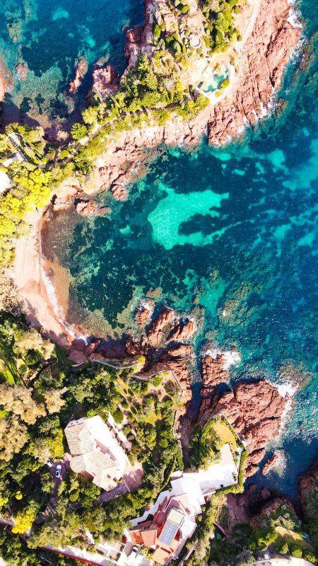 Aerial view of a turquoise cove between red rocks on the Estérel coast