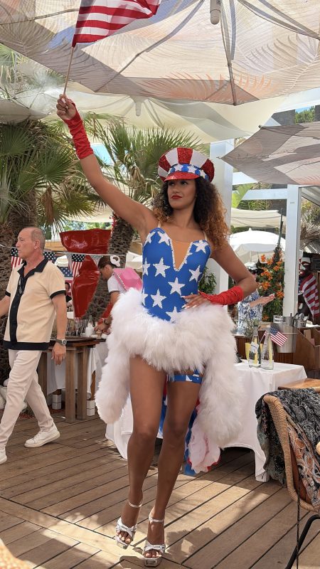Entertainer in costume dancing on the terrace of a beach club at Tahiti Beach, Pampelonne